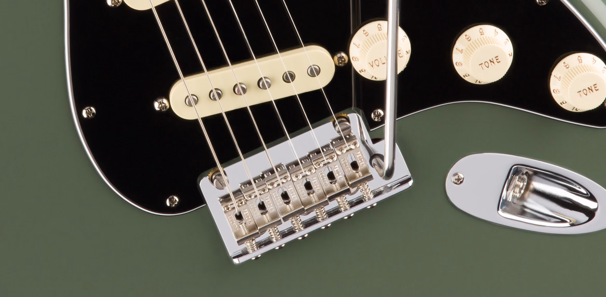 A close-up of a guitar fretboard showing the strings running over the frets, where a plucked string's fixed length and tension are set.