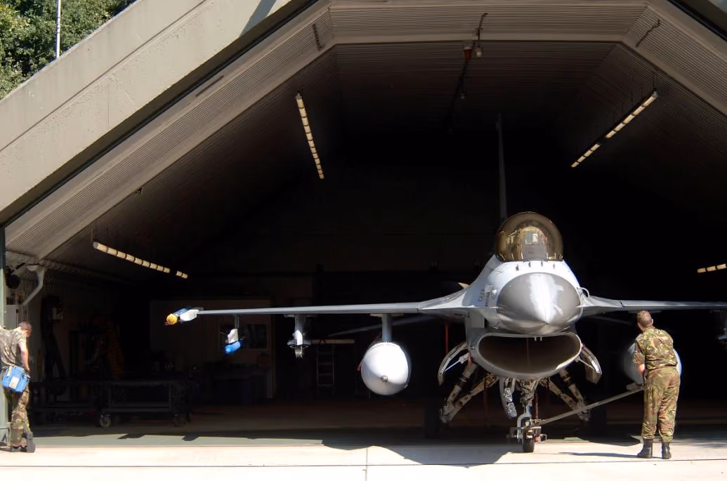 An F-16 parked inside its hangar on the flight line