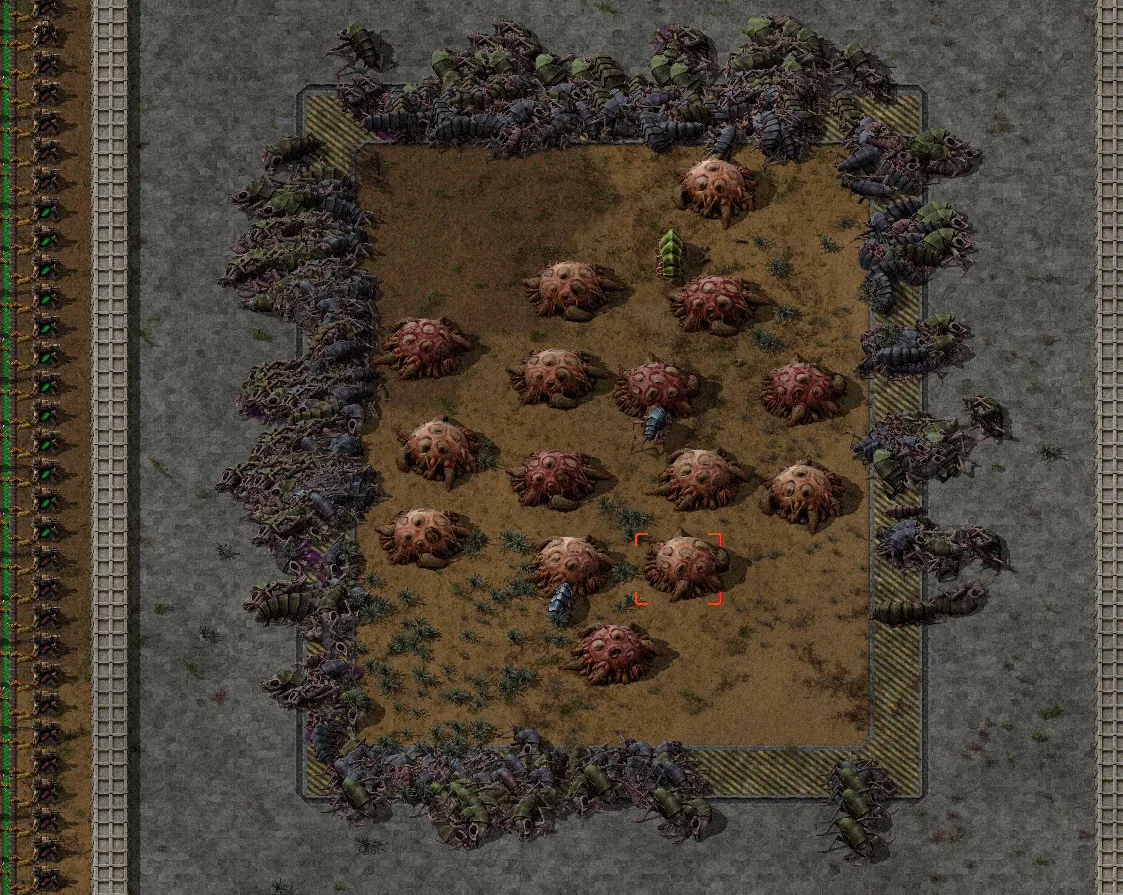 A wiki screenshot of a walled concrete enclosure containing over a dozen biter nests and worms, sitting beside a base's rail line and perimeter wall
