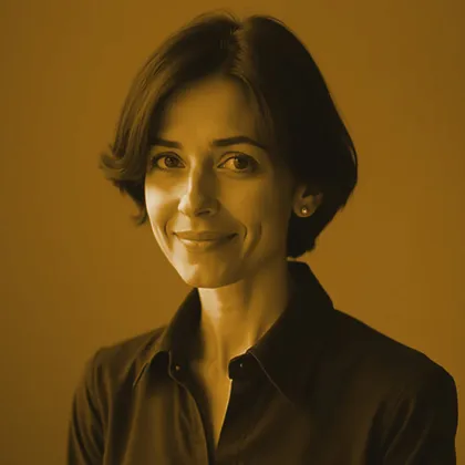 A staff portrait, toned in the site's gold and bronze. A woman in middle age with a short dark bob and a dark collared shirt, turned three-quarters to the camera and half-smiling, lit from one side against a plain warm wall.