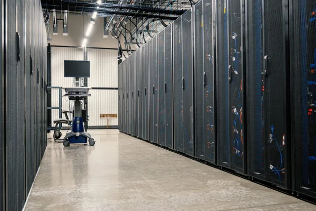 A row of server racks in a data centre aisle, cables running overhead.