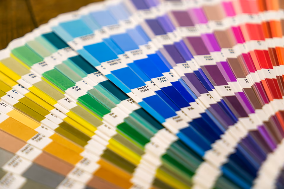 A fanned-out deck of Pantone colour swatch cards arranged in a spectrum from yellow through blue to red