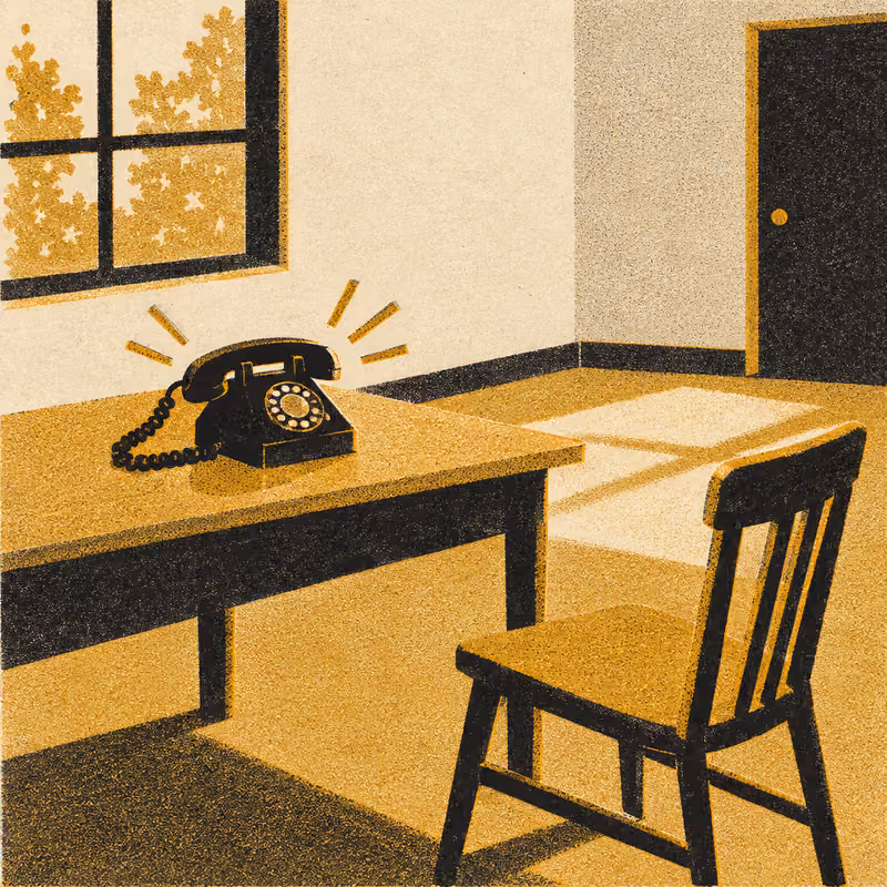 A telephone ringing on a desk in an empty room, its chair pushed back and empty