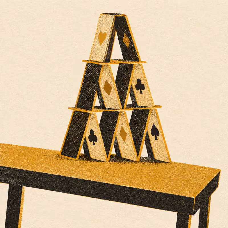 A house of cards standing perfectly still on a table that is visibly tilting to one side beneath it