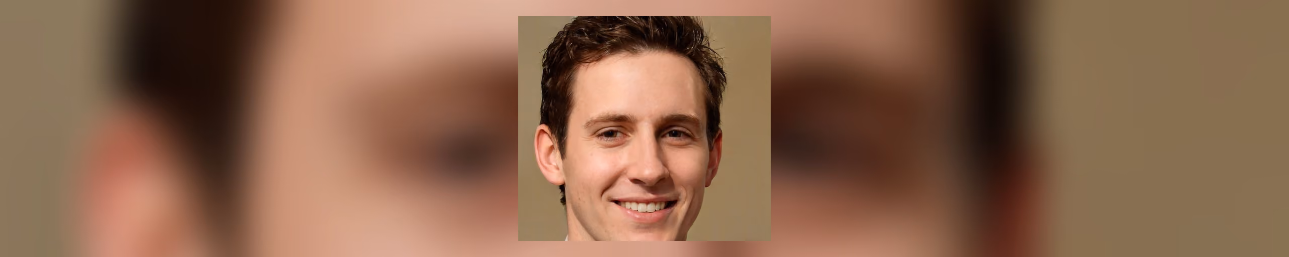 A photographic portrait of a man with short side-parted brown hair, smiling and facing the viewer against a plain tan background.