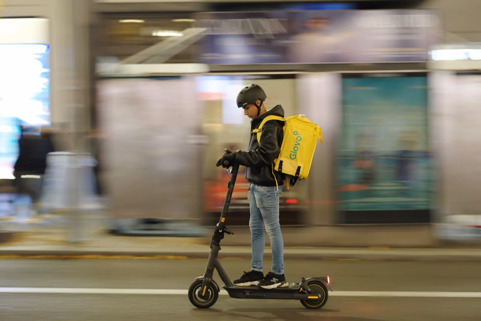 A delivery rider on a scooter, moving through traffic