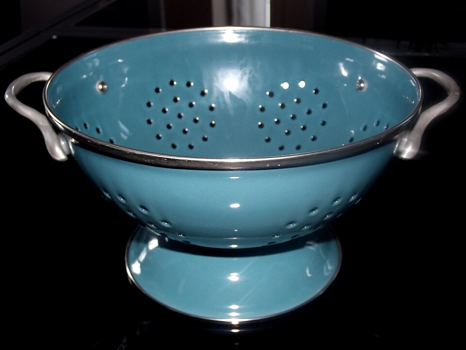 A blue plastic colander with perforated holes, used to separate solid food from liquid