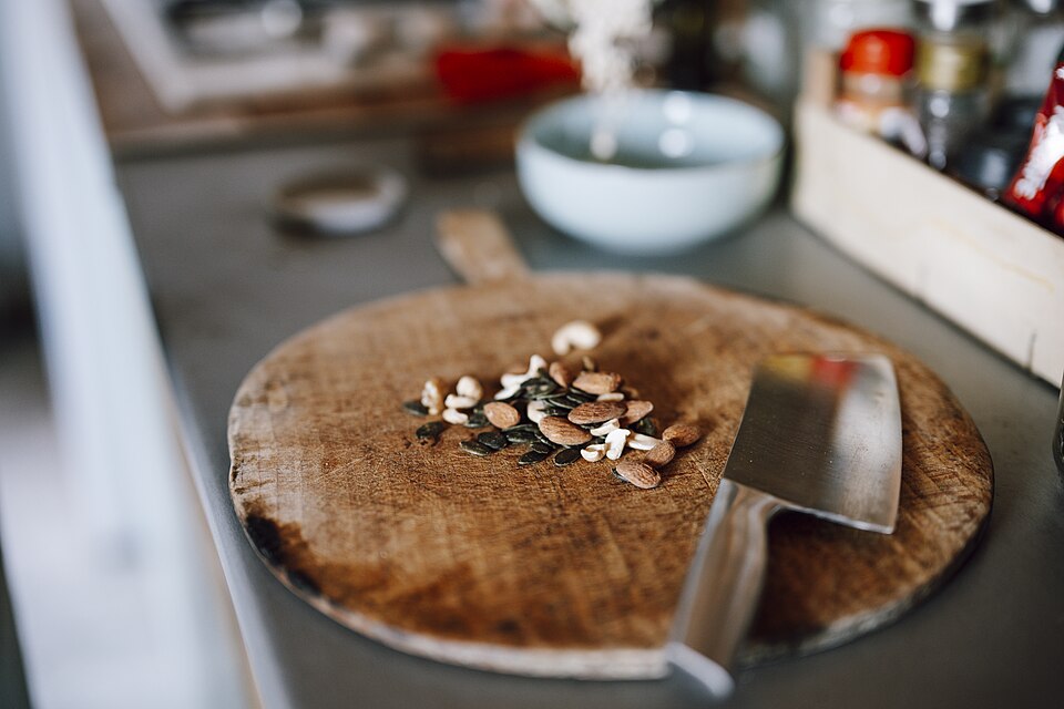 Chopped nuts and herbs on a wooden cutting board in a kitchen setting
