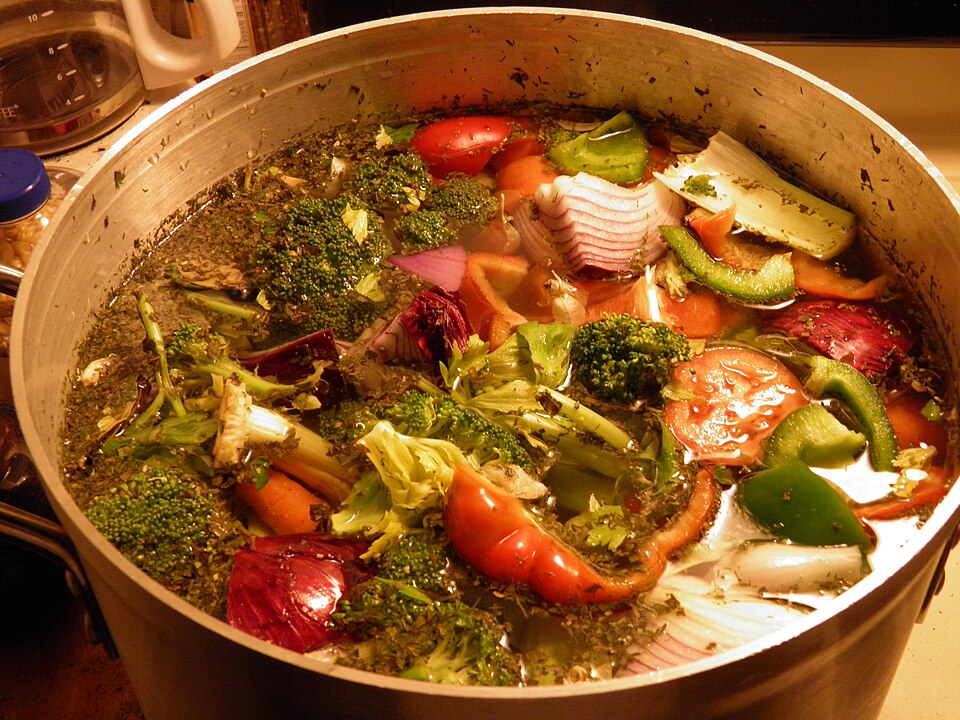 Large stockpot simmering on a stove, holding a stock finished well ahead of service