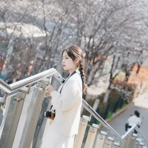 Portrait of Suika Wang beside an outdoor stairway with a camera.