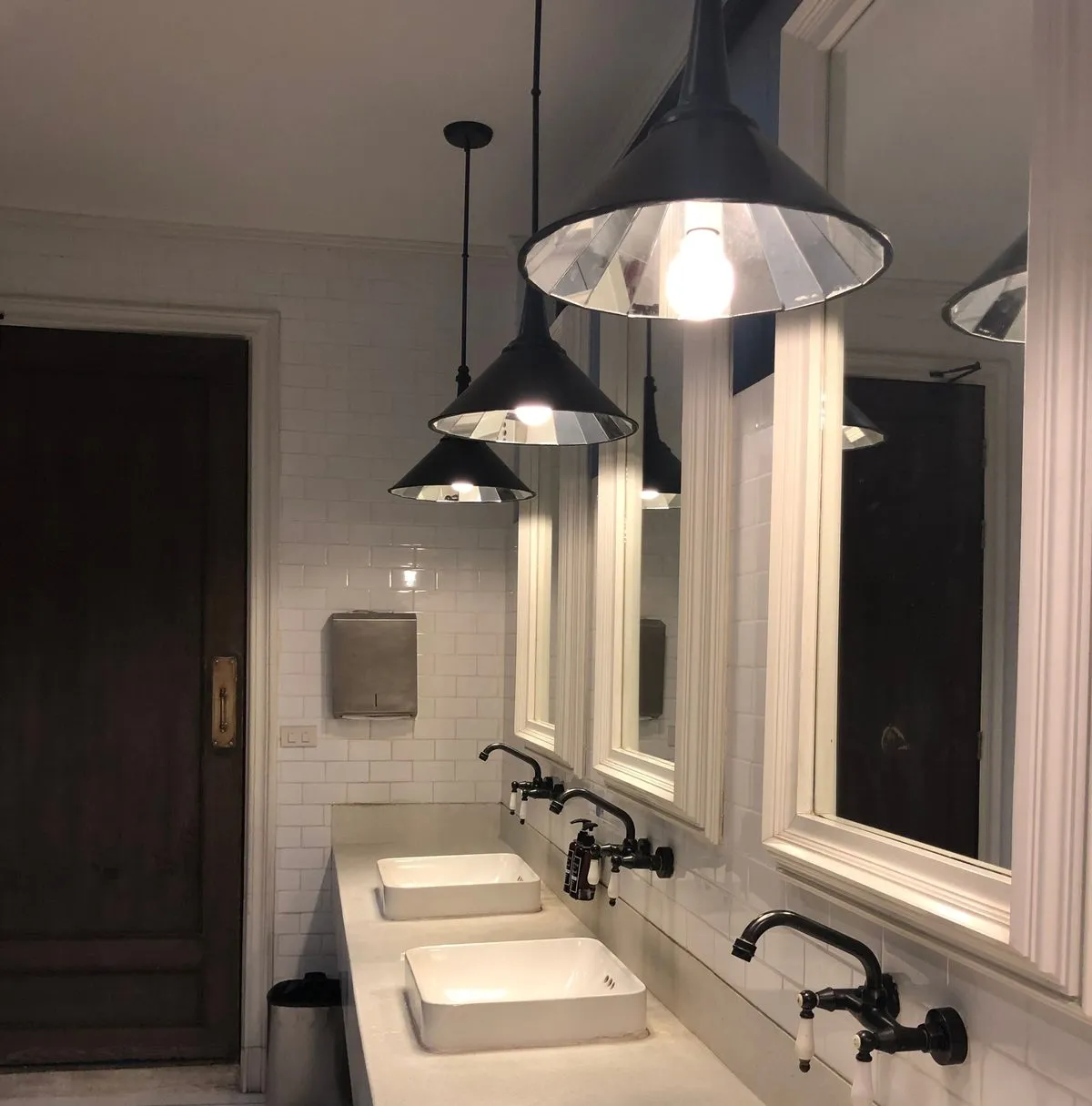 Bad manner: a row of restroom sinks and mirrors, empty and silent — the
kind of quiet a loud phone call in a nearby stall would
break.