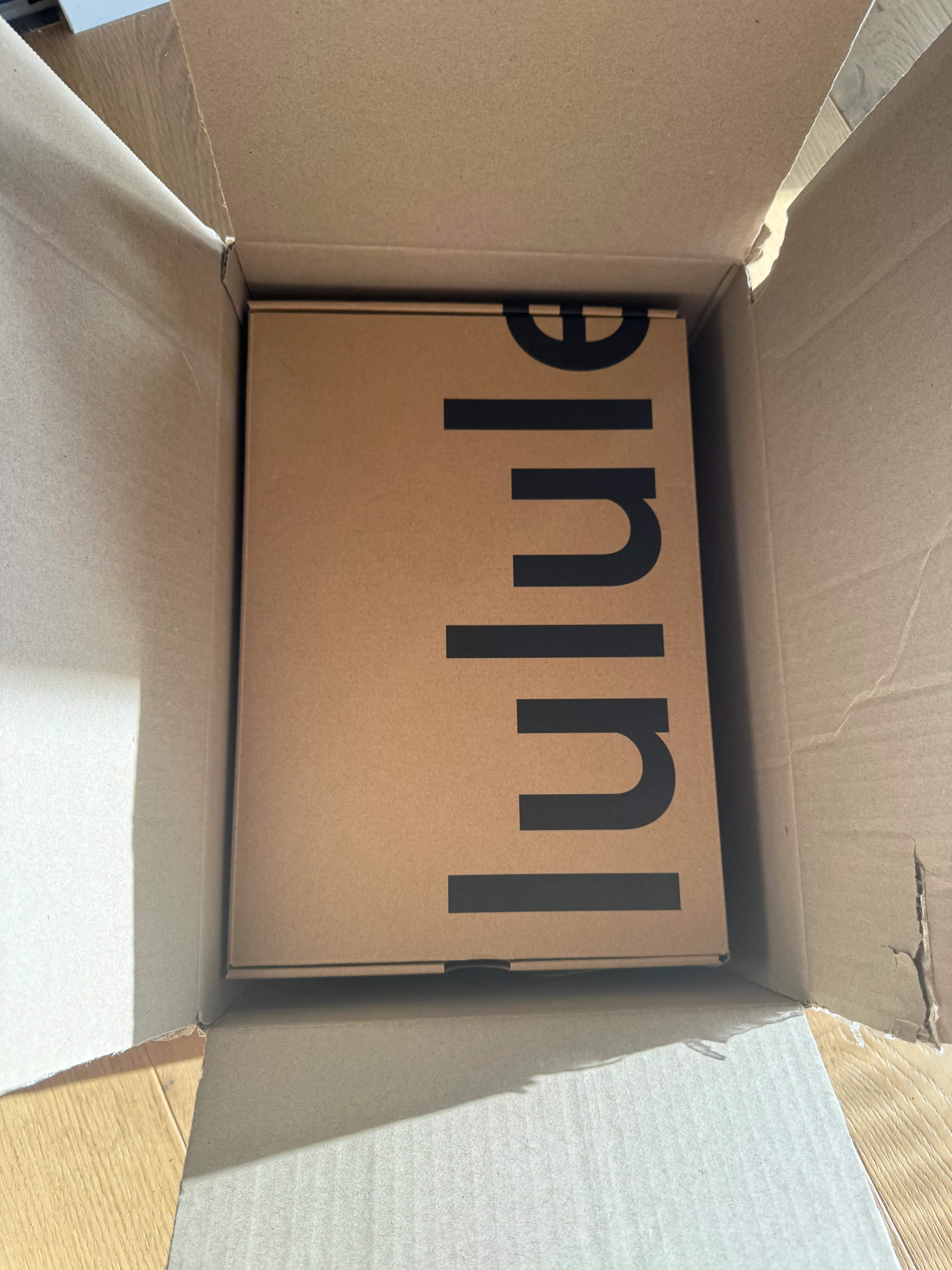 Looking down into an oversized outer shipping box, with a much smaller lululemon-branded product box sitting inside it